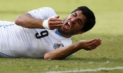 Striker Timnas Uruguay, Luis Suarez, terjatuh usai 'tabrakan' dengan pemain Italia, Giorgio Chiellini, di laga terakhir Grup D Piala Dunia 2014 Brasil di Arena Dunas, Natal, Selasa (24/6). 