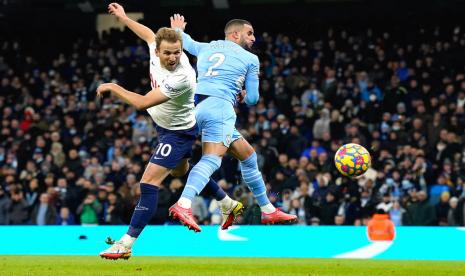 Striker Tottenham Hotspur, Harry Kane (kiri) menyundul bola yang akhirnya berbuah gol ke gawang Manchester City pada laga Liga Primer di Stadion Etihad, Ahad (20/2/2022). Tottenham menang 3-2 pada laga ini.