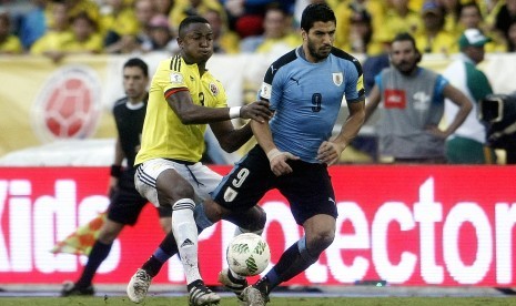 Striker Uruguay, Luis Suarez (kanan) diganjal oleh bek Kolombia, Oscar Murillo pada laga kualifikasi Piala Dunia 2018 di stadion Metropolitano, Barranquilla, Rabu (12/10). Laga berakhir imbang 2-2.