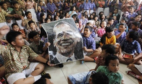 Students at State Elementary School Menteng 01, where U.S. President Barack Obama studied from 1970-1971, hold a poster with an image of Obama while watching TV coverage of the U.S. presidential election in Jakarta November 7, 2012.   