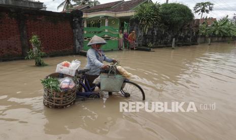 Subarti (40), berjualan sayur melewati genangan banjir di Desa Karangjati, Sampang, Cilacap, Jawa Tengah, Selasa (27/10/2020). Hujan deras yang mengguyur wilayah selatan Jateng akibat dampak dari fenomena La Nina, selama dua hari terakhir, menyebabkan banjir dan longsor pada sejumlah wilayah di Kabupaten Kebumen, Cilacap, dan Banyumas.