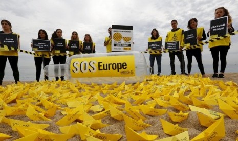 Sukarelawan dari Amnesty International melakukan aksi meletakkan kapal kertas di sebuah pantai di Barcelona, Spanyol. Kapal yang diberi tulisan SOS Europe itu merupakan keprihatinan dari banyak imigran yang meninggal di kapal saat hendak masuk ke Eropa.