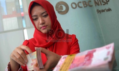 Suntikan Modal BUS Dan UUS: Teller menghitung uang rupaih di Banking Hall OCBC NISP Syariah, Jakarta, Kamis (12/2).