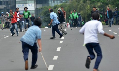 Supir taksi dan pengemudi ojek berbasis aplikasi saling lempar batu saat aksi menolak keberadaan angkutan umum online di Jakarta, Selasa (22/3). 