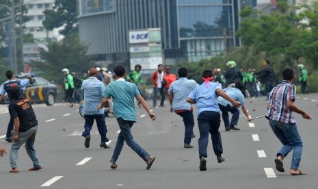 Sopir taksi dan pengemudi ojek berbasis aplikasi saling lempar batu saat aksi menolak keberadaan angkutan umum online di Jakarta, Selasa (22/3).