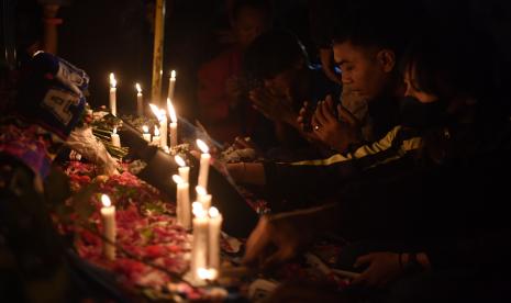 Suporter Arema FC (Aremania) berdoa di depan Patung Singa Stadion Kanjuruhan, Malang, jawa Timur, Ahad (2/10/2022).