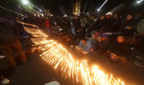 Suporter Arema FC (Aremania) berdoa sambil menyalakan lilin di Stadion Gajayana, Malang, Jawa Timur, Ahad (2/10/2022). Kegiatan tersebut sebagai bentuk duka cita atas jatuhnya korban jiwa pada kerusuhan di Stadion Kanjuruhan. 