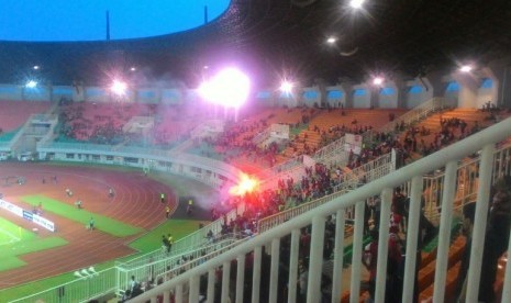 Suporter Indonesia di tribun selatan menyalakan suar di Stadion Pakansari setelah pertandingan Indonesia vs Myanmar, Selasa (21/3).