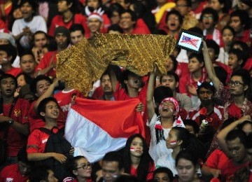 Suporter Indonesia mengacungkan kain bermotif batik dan bendera Merah Putih.