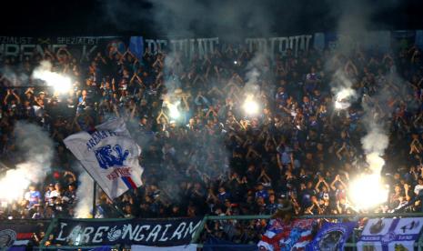 Suporter kesebelasan Arema FC (Aremania) menyalakan api suar saat mendukung tim kesayangannya bertanding melawan kesebelasan RANS Nusantara FC dalam pertandingan uji coba di stadion Kanjuruhan, Malang, Jawa Timur, Selasa (7/6/2022). Di akhir babak pertama Arema sementara unggul dengan skor 1-0. 