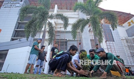 Suporter Persebaya (Bonek) menanam pohon di bagian depan Stadion Gelora Bung Tomo (GBT) saat mengikuti aksi bersih-bersih di Surabaya, Jawa Timur, Jumat (8/11/2019).