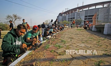 Suporter Persebaya (Bonek) mengecat tepi jalan menuju Stadion Gelora Bung Tomo (GBT). Stadion GBT menjadi salah ssatu venue Piala Dunia U-20 2021.