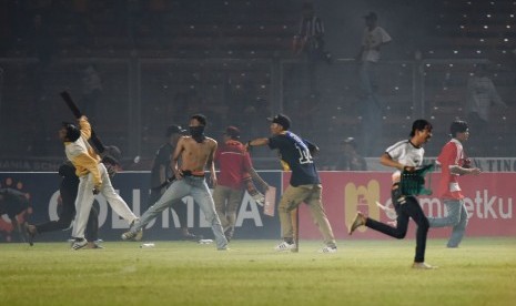 Suporter Persija Jakarta melempari petugas kepolisian ketika terlibat kericuhan pada laga Torabika Soccer Championship di Stadion Utama Gelora Bung Karno, Jakarta, Jumat (24/6). 