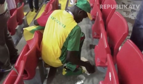 Suporter Senegal saat membersihkan sampah disekitar tribun stadion usai laga.