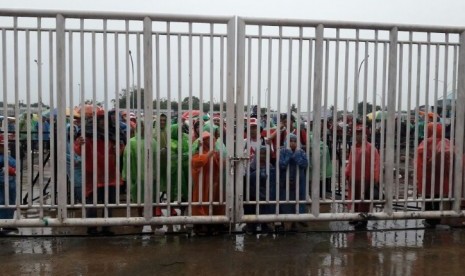 Suporter timnas Indonesia menunggu masuk Stadion Pakansari di tengah guyuran hujan, Rabu (14/12) sore.