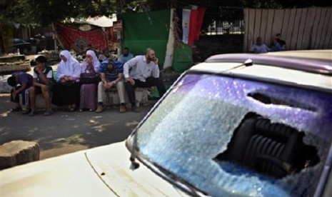 Supporters of Egypt's ousted President Mohammed Morsi sit next to a damaged car during clashes with Police, where protesters have set up a camp near Cairo University in Giza, Egypt, Tuesday, July 23, 2013. 