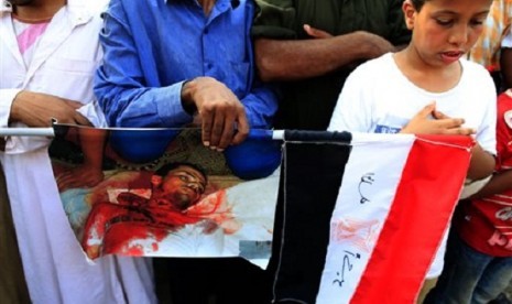 Supporters of ousted President Mohammed Mursi pray as they hold a picture of man killed during clashes with Egyptian security forces, at the Republican Guard building in Nasr City, Cairo, Egypt, Tuesday, July 9, 2013.