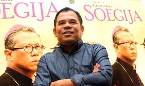 Sutradara Garin Nugroho berdiri di depan poster film 