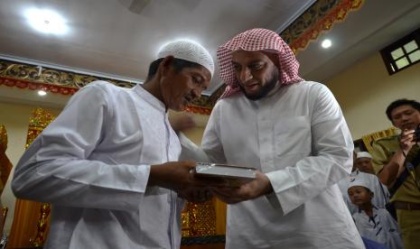 Syekh Ali Jaber (kanan) memberikan Alquran kepada salah seorang warga Suku Anak Dalam.