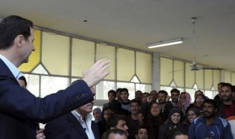 Syria's President Bashar al-Assad (left) speaks to displaced Syrians during his visit to them in the town of Adra in the Damascus countryside, March 12, 2014.