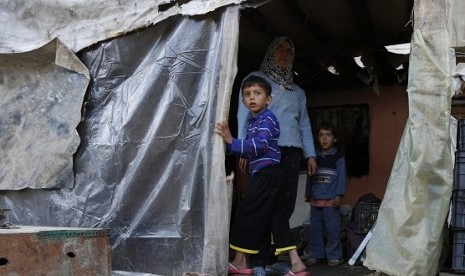 Syrian refugee Am Ahmed stands with her children at her temporary home in a garage where she lives with her family in Bar Elias village in the Bekaa valley December 13, 2012.  