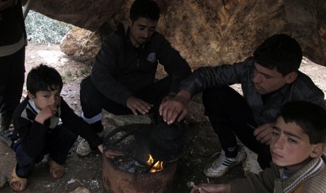 Syrian refugees warm themselves by a fire at a refugee camp in Atimeh, on the Syrian-Turkish border of the Idlib Governorate December 10, 2012. Picture taken December 10, 2012.   