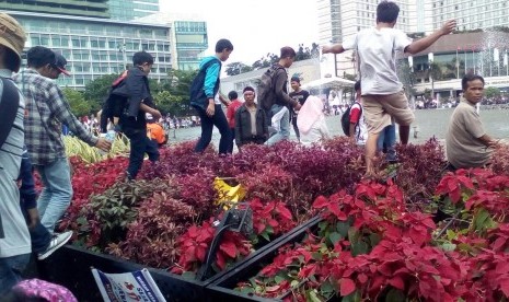 Taman di sekitar Bundaran HI, Jakarta, tampak rusak terinjak-injak saat aksi Parade Kebudayaan digelar pada Ahad (4/12). Terlihat spanduk gambar atribut partai tertentu tergeletak di sekitar taman.