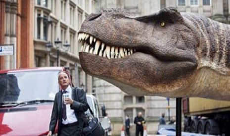 Tampak seorang pekerja yang kaget ketika melihat sosok dinosaurus T-Rex dalam perjalanan ke tempat kerja di kota Birmingham, Inggris.