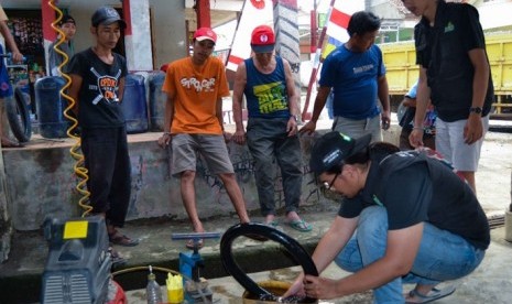 Tampak siswa KKN sedang mempraktekkan penambalan ban sepeda motor kepada warga