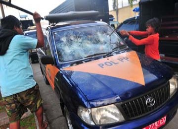 Tampak mobil milik Satpol PP dihancurkan massa saat insiden di Tanjung Priok, Rabu (14/4).