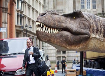 Tampak seorang pekerja yang kaget ketika melihat sosok dinosaurus T-Rex dalam perjalanan ke tempat kerja di kota Birmingham, Inggris.