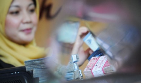 Teller bank syariah sedang menghitung uang nasabah (ilustrasi)