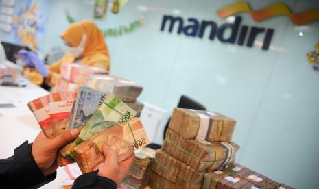 Teller menata tumpukan uang di Kantor Bank Mandiri Cabang Braga, Bandung, Jawa Barat. PT Bank Mandiri (Persero) Tbk fokus membidik penyaluran kredit ke sektor berkelanjutan dan infrastruktur. Tercatat dari penyaluran kredit Bank Mandiri sebesar Rp 1.072,9 triliun pada kuartal I 2022 atau tumbuh 8,93 persen secara year on year.