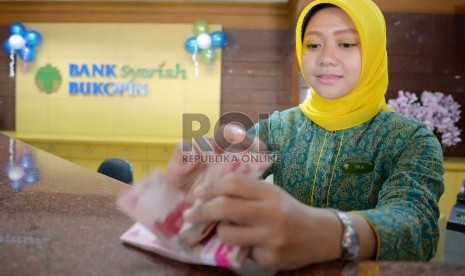  Teller menghitung rupiah di banking hall Bank Syariah Bukopin (BSB) di Jakarta, Rabu (21/1). ( Republika/ Yasin Habibi)