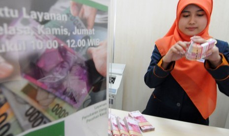  Teller menghitung uang nasabah di salah satu bank syariah. 