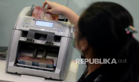 Teller menghitung uang rupiah di Bank Mandiri, Jakarta, Jumat (13/3). Volume transaksi kartu kredit Bank Mandiri turun 10 persen pada Maret dibandingkan Februari.