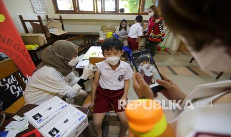 Tenaga kesehatan menyuntikan vaksin Covid-19 ke murid sekolah dasar di Sekolah Yos Sudarso, Kota Batam, Provinsi Kepulauan Riau, Selasa (14/12/2021).