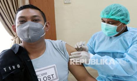 Tenaga kesehatan menyuntikkan vaksin COVID-19 dosis ketiga kepada anggota polisi saat vaksinasi booster. ilustrasi