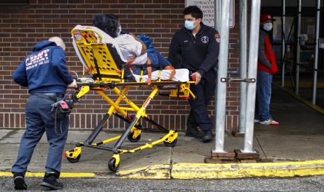 Tenaga medis mengenakan masker pelindung saat membawa pasien masuk ke rumah sakit di New York, Amerika, Ahad (29/3). Covid-19 bisa menyerang kelompok usia mana pun dengan sejumlah gejala mulai dari ringan hingga berat. 