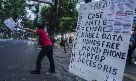 Tenaga pemasaran menawarkan pelayanan perbaikan gawai dan laptop di depan Mal Bandung Electronic Center Bandung, Jawa Barat, Sabtu (31/7/2021). Sejumlah pedagang yang membuka toko di Mal Bandung Electronic Center tersebut terpaksa menggunakan bahu jalan dalam berjualan dan melayani perbaikan gawai dan laptop pelanggan akibat belum adanya lapak pengganti selama mal dan pusat perbelanjaan ditutup di masa PPKM.