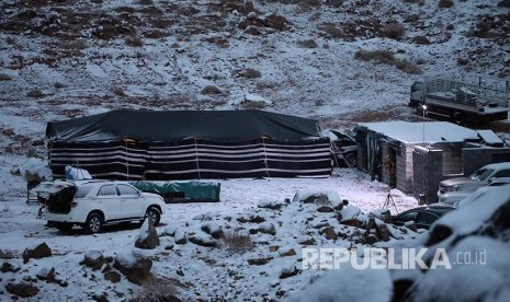 Tenda didirikan di dekat mobil yang diparkir saat salju turun di Provinsi Tabuk, Arab Saudi. Sebagian Arab Saudi Diprediksi Dilanda Badai Debu, Petir, dan Salju Hingga Jumat