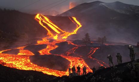 Tentara Angkatan Darat Spanyol berdiri di atas bukit saat lava mengalir saat gunung berapi terus meletus di pulau Canary La Palma, Spanyol, Senin, 29 November 2021. Beberapa ventilasi vulkanik baru dibuka di La Palma pada hari Minggu, melepaskan lava baru yang mengalir cepat menuruni punggung bukit dan mengancam akan memperluas dampak pada tanah, infrastruktur, dan rumah yang dievakuasi.