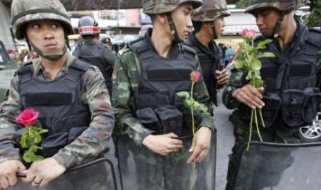 Tentara berjaga-jaga di Bangkok, sambil memegang bunga yang diselipkan pendukung mereka menyusul konflik berkepanjangan di Thailand.