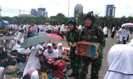 Tentara berjilbab bagikan air mineral kepada peserta Aksi Super Damai di Monas, Jumat (2/12).