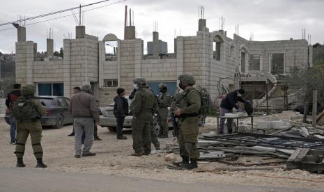 Tentara Israel berdiri di samping mobil yang menurut pemilik Palestina ban mereka disayat dan disemprot dengan Bintang Daud dan Ibrani oleh pemukim Yahudi, di desa Qira dekat kota Salfit, Tepi Barat, Ahad 23 Januari 2022.