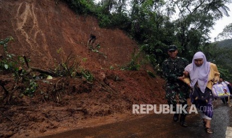 Tentara membantu salah satu warga berjalan saat evakuasi longsor di Jalur Utama Puncak, Bogor, Jawa Barat, Senin (5/2). 