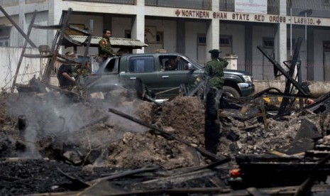  Tentara Myanmar melintasi bangunan yang terbakar yang menampung sebuah panti asuhan untuk anak-anak Muslim di Lashio, Myanmar, Kamis (30/5).     (AP/Gemunu Amarasinghe)