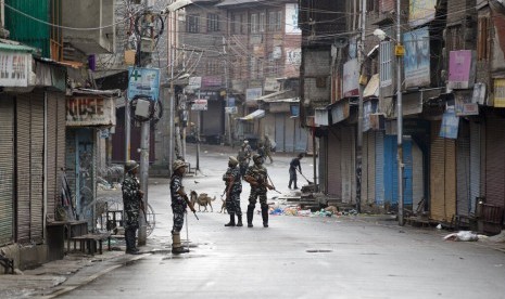 Tentara paramiliter India berjaga di jalanan yang sepi saat jam malam di Srinagar, Kashmir yang dikuasai India, Kamis (8/8).