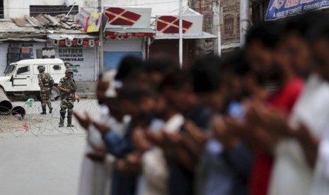 Tentara paramiliter India berjaga saat Muslim Kashmir menunaikan shalat Jumat di jalan di luar masjid setempat saat jam malam di Srinagar, India.