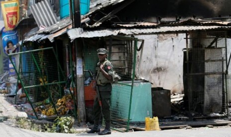 Tentara Sri Lanka berdiri di dekat toko yang dirusak di Kandy, Sri Lanka, 8 Maret 2018.